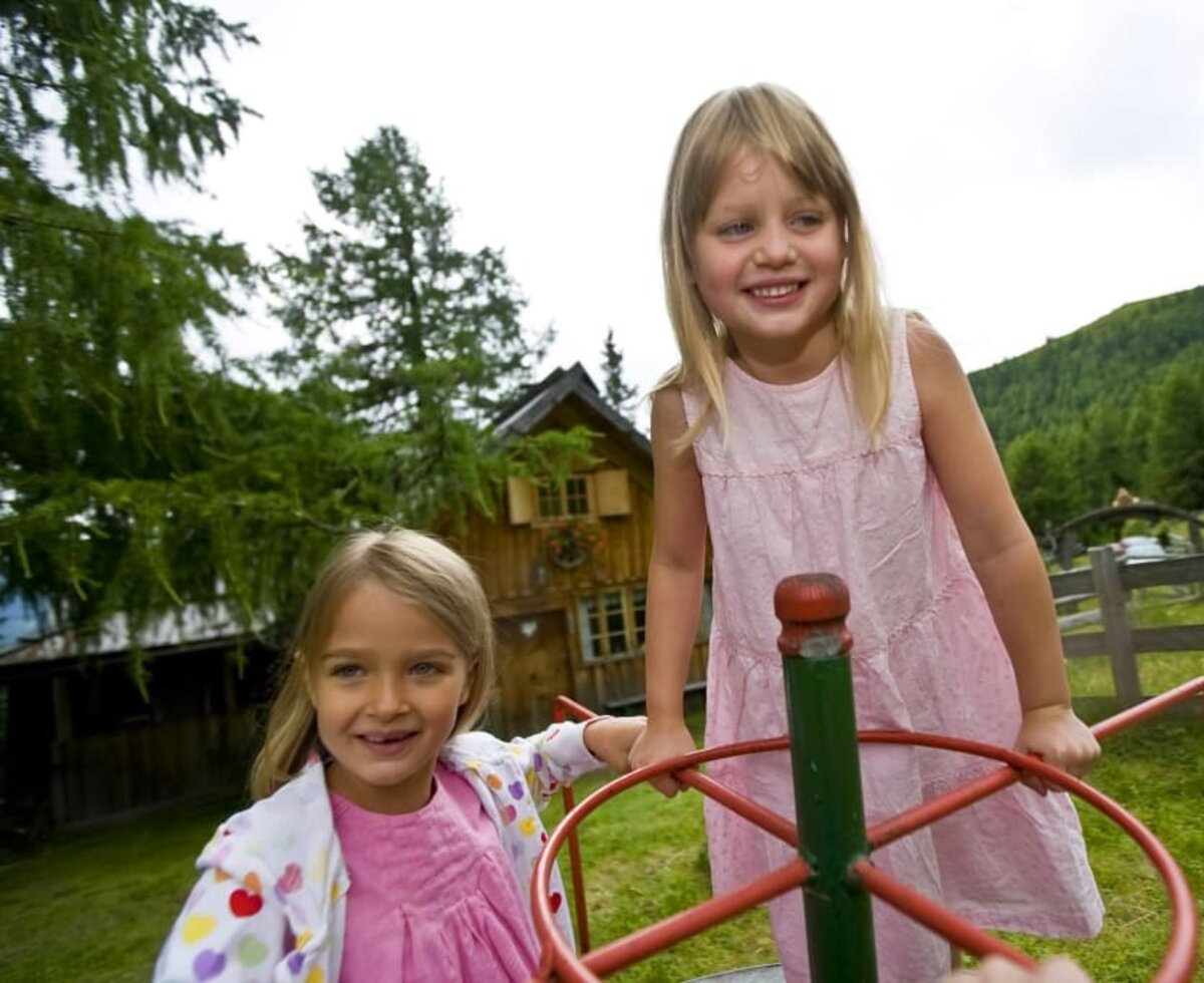 Mädchen spielen vor Hütte