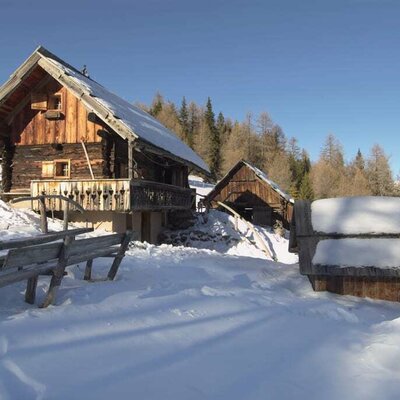 Außenansicht der Hütte mit altem Stall im Winter