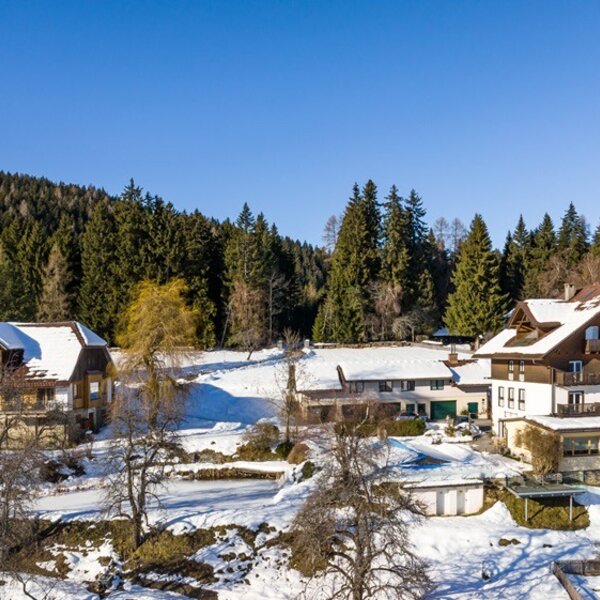 Der Bauernhof mit seinen Gebäuden inmitten einer schneebedeckten Landschaft am Waldrand. Der Bauernhof mit seinen Gebäuden inmitten einer schneebedeckten Landschaft am Waldrand.