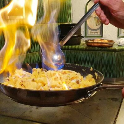 beliebter Kaiserschmarrn flambiert auf dem Holzofen