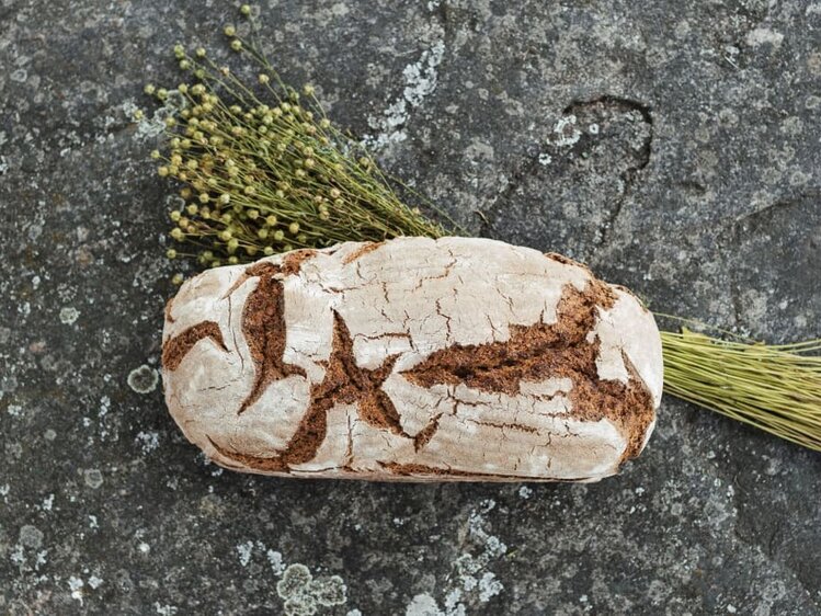 Frisch gebackenes Brot liegt mit Gemeinem Lein auf einer Granitplatte | © Urlaub am Bauernhof Oberösterreich / Biohof Schafflhof