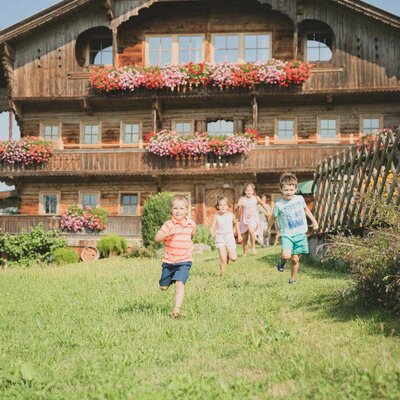 Kinder laufen über die Wiesen vor unserem Haus - im 1. Stock befinden sich die Ferienwohnungen