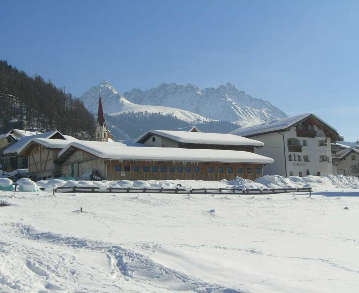 Rosenhof (Hof und Haus) im Winter. Das Skigebiet Bergkastel im Hintergrund.